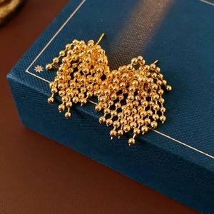 Close-up of gold fireworks tassel earrings with metallic bead clusters on velvet base