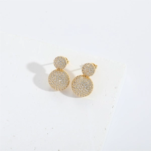 Close-up of gold double ball earrings with pave zircon crystals on marble stone