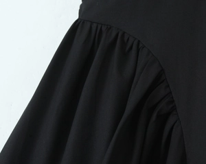 Detail shot of the black pleated fabric and fine stitching on a deep V-neck maxi dress