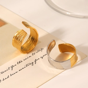 Close-up of 18K gold-plated textured open rings with hammer finish on vintage paper