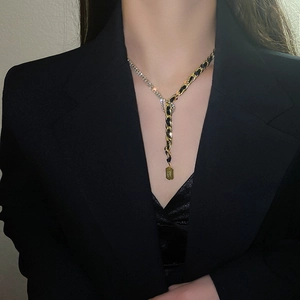 Détail d'un collier en Y doré avec maillons strass et chaîne tissée sur un mannequin