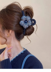 Détail d'une pince à cheveux fleur en laine tricotée bleu et gris avec perle centrale