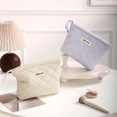 Detailed close-up of quilted beige and lavender cosmetic bags with rectangular labels