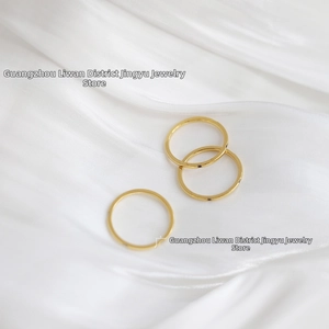 Close-up of three stacked 18K gold-plated titanium steel rings on white silk background