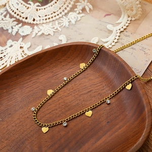 Detail of gold titanium heart necklace with rhinestones on vintage wooden plate