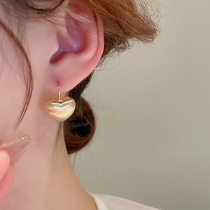 Macro detail of high-shine gold-plated heart drop earring on model with elegant style
