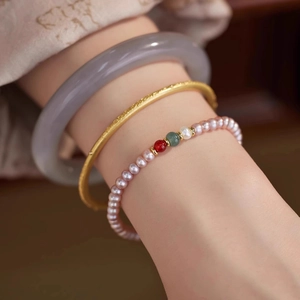 Macro detail of freshwater pearl bracelet with agate beads and frosted gold bangle set