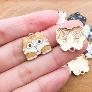 Detail of cute cat enamel pendant showing front and back views on a finger