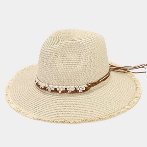 Detailed view of beige straw hat featuring woven bands and fringe tassels on the brim