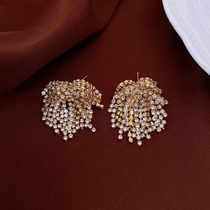 Elegant gold tassel earrings with shimmering rhinestones on dark fabric background