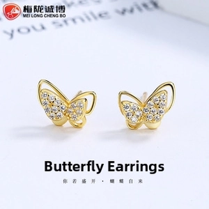 Macro shot of gold butterfly earrings with cubic zirconia and hollow wing details