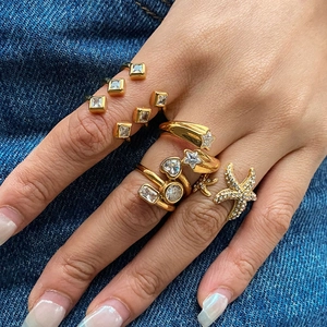 Set of gold titanium steel rings with star and heart designs on denim background