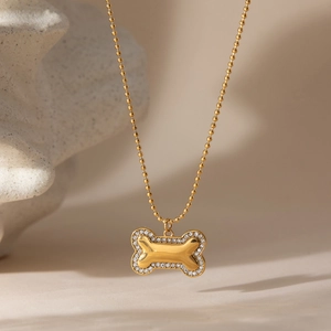Detailed view of gold dog bone pendant with sparkling zircons on a delicate bead chain