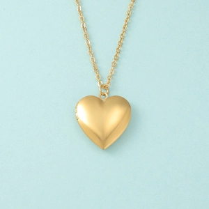 Detail showing a golden heart-shaped locket pendant with a polished mirror finish