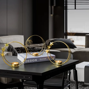 Set of three gold metal circle candle holders with angel and star ornaments on black table