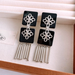 Détail de boucles d'oreilles vintage en résine avec nœud argenté et franges en métal