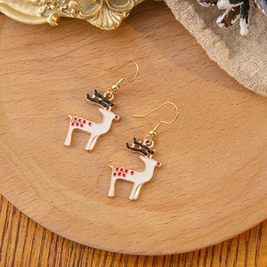 Detail view of festive reindeer drop earrings with gold trim on a wooden display