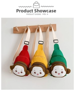 Three monkey-shaped kids chest bags in red, yellow, and green on a white wall hook