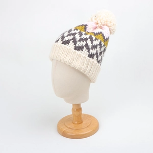 Close-up of geometric jacquard knit pattern and soft pom-pom on warm winter beanie