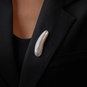 Matte silver streamlined brooch on a black suit lapel, elegant metallic accessory