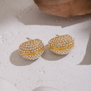 Macro detail of gold stud earrings with pave-set rhinestones and a grooved design