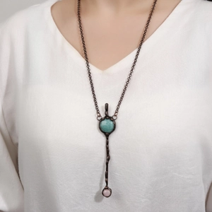 Retro long necklace with amazonite pendant, pink bead, and bronze chain on white shirt
