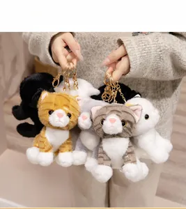 Detailed view of various cute plush cat keychains with gold metal rings in hand