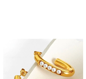 Close-up of elegant gold U-shaped earrings featuring five small white pearls on a display