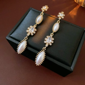 Close-up of vintage gold tassel earrings with oval pearls and zircons on black leather