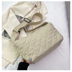 Detail of beige quilted corduroy tote with adjustable wide strap and black buckles