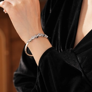 Macro detail of silver clasp bangle with round cubic zirconia on black velvet