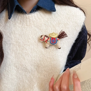 Detailed close-up of a handmade pony brooch featuring colorful embroidery on a white vest