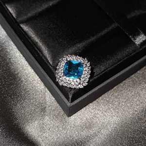 Macro shot of a floral ring with a square blue gemstone and double rows of white diamonds
