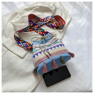 Close-up of ethnic bucket bag with blue canvas, colorful embroidery and tassel detail