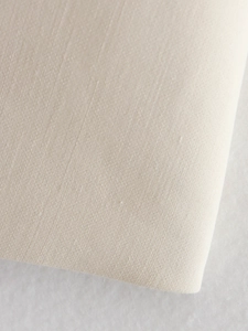 Close-up of beige textile fabric showing detailed linen-like texture and fine fibers