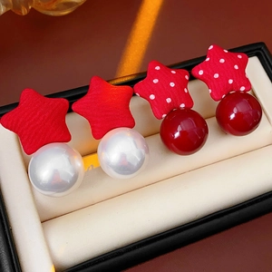 Detailed view of red star fabric earrings with pearl and red beads in a jewelry box