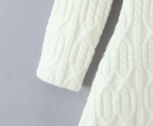 Detailed close-up of white cable knit dress showing texture and shoulder stitching