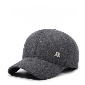 Detail view of the silver metal logo on a thick dark grey winter baseball cap for men