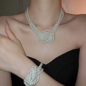 Detailed view of layered pearl necklace and bracelet set with knotted design