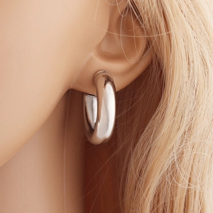 Gros plan sur une boucle d'oreille créole argentée de 28mm avec finition polie brillante
