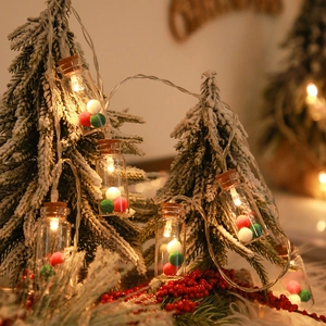 Detail of warm white LED Christmas wishing bottles with colorful pom poms on mini tree