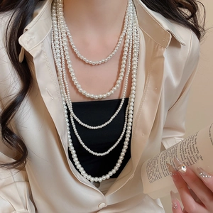 Close-up of elegant multi-layer cream pearl necklace styled on a champagne silk shirt