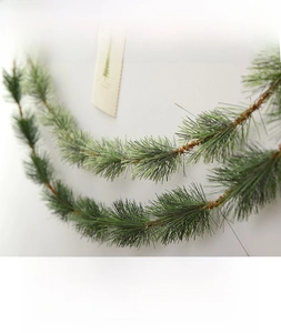 Detail of 5.5m dense artificial pine garland for festive Christmas decoration on white wall