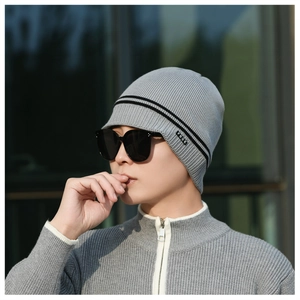Detail of grey winter knit beanie featuring dual black stripes and FBQE logo label