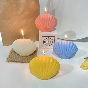 Vue détaillée de bougies en forme de coquillage colorées avec flamme et coffret cadeau