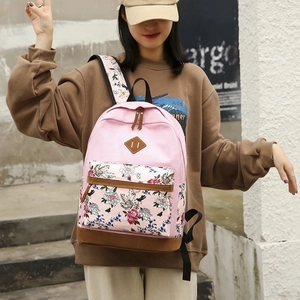Pink floral backpack with leather base worn by a model against a minimal wall background