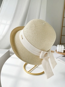 Détail du chapeau de paille beige avec ruban élégant et logo métallique doré chic