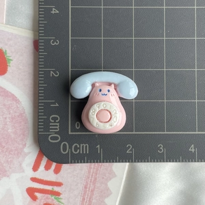 Pink and blue cartoon phone resin charm on a ruler showing 2.5cm x 1.8cm size