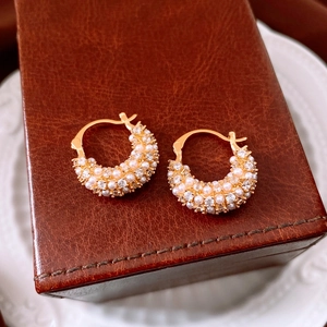 Close-up detail of 18k gold plated hoop earrings with pearls and zircon on leather