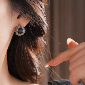 Close-up of flower stud earring with black center stone and sparkling rhinestones